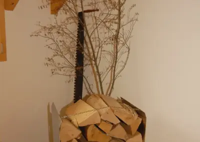 Holzstapel in modernem Innenraum neben Metallteilen und Holzleiste unter schrägem Dachfirst für kreative Deko.