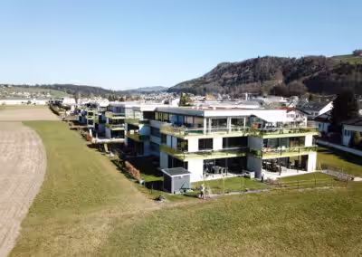 Moderne Wohnanlage in ländlicher Umgebung mit Bergblick und blauen Himmel. Ideal für naturnahes Wohnen.