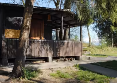 Holzhütte im Wald mit Veranda, umgeben von Bäumen und Natur, ideal für einen ruhigen Rückzugsort in der Natur.