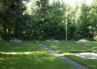 Minigolfplatz im Grünen, sonniger Tag, ruhige Atmosphäre, Bäume im Hintergrund, perfekt für Outdoor-Sport und Freizeit.